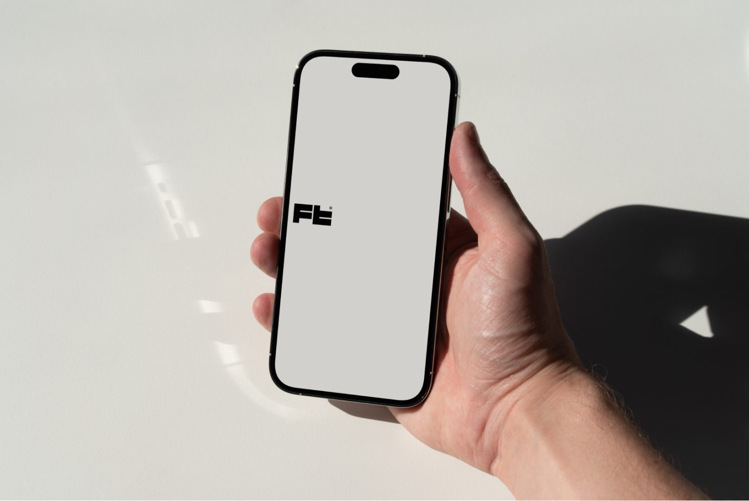 Hand holding smartphone mockup with blank screen for design presentation, on a light background with subtle shadows, suitable for app interface display.